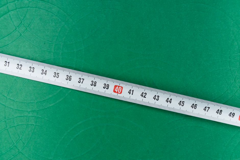 Tape measure laid across a flat green surface, used for working out lawn square footage
