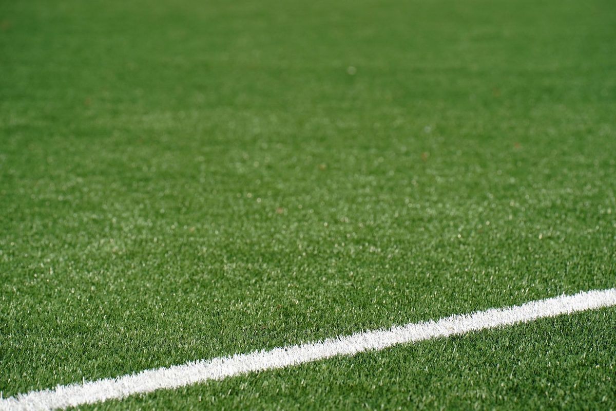 Close view of a green synthetic turf sports field with a painted white boundary line